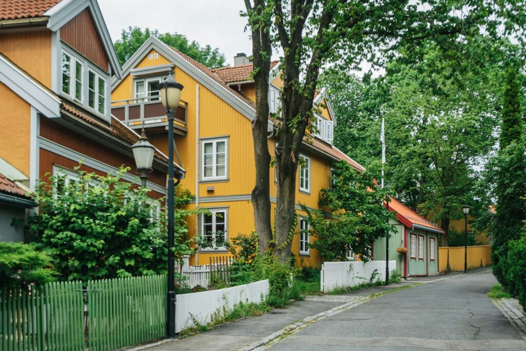 a yellow house with a red roof and a green fence